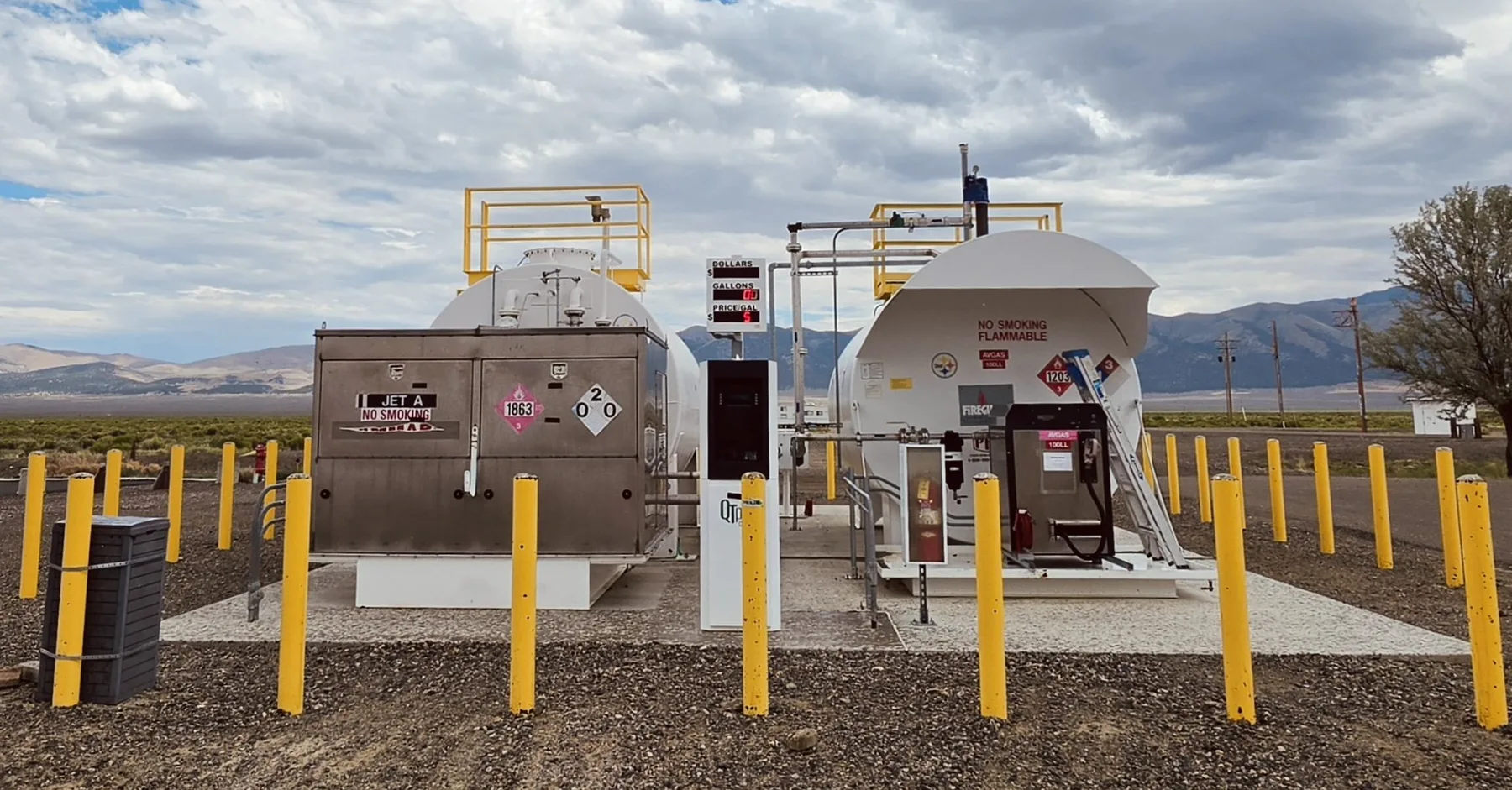 Self-serve 100LL and Jet-A fuel tanks and pumps on the ramp at Austin Airport, with mountains and sky in the background